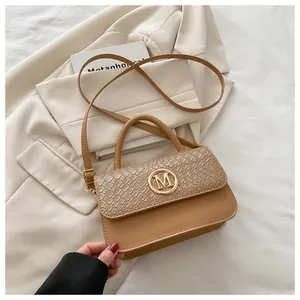 Détail du sac à main camel avec logo M doré et rabat à motif crocodile embossé