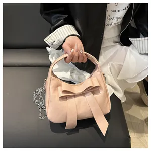 Vue détaillée du sac à main rose pâle avec un grand nœud et une bandoulière en chaîne
