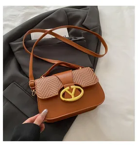 Close-up of vintage brown crossbody bag with woven texture and gold circular logo detail