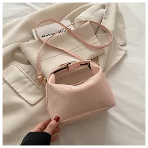 Detailed overhead view of a light pink snakeskin textured crossbody bag with gold hardware