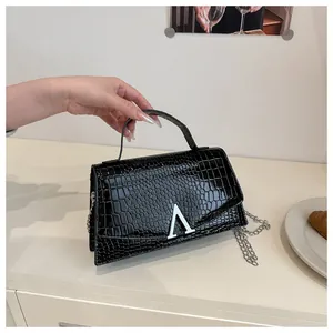 Detail of black crocodile texture handbag featuring silver V-shaped buckle and chain