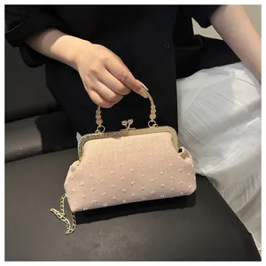 Dettaglio borsa retrò color crema con trama floreale e manico in metallo dorato
