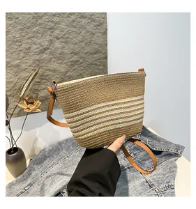 Detail of woven straw bucket bag showing brown and white stripes with leather strap