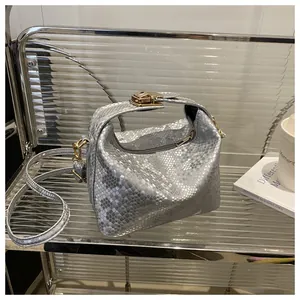Detail of silver snakeskin texture handbag with golden twist lock and metallic finish