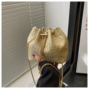 Détail du sac seau en paille avec cordon, chaîne dorée et pendentifs en perles