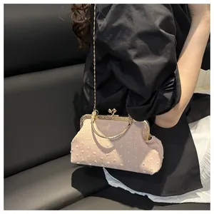 Dettaglio della borsa da sera in tessuto rosa con manico dorato e tracolla su sedile nero