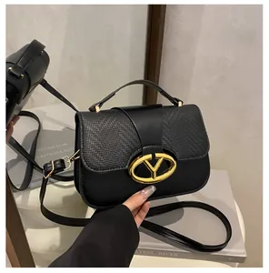 Detail of black leather handbag featuring woven flap texture and gold Y-shaped clasp