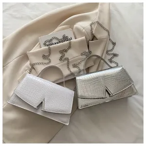 Top view of white and silver crocodile textured mini handbags with V-shaped metal buckles