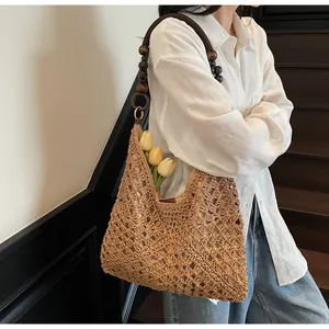 Detail of woven straw tote bag featuring ethnic style wooden bead handle and tulip decoration
