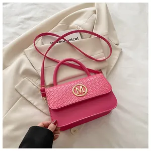 Vue détaillée du rabat rose à relief crocodile avec boucle métallique dorée en forme de M