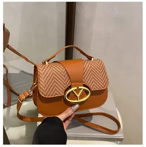 Detail of a brown leather bag with a woven texture flap and golden oval metal lock buckle