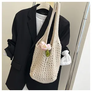 Detail of a beige knit tote bag with floral accents over a stylish blazer outfit