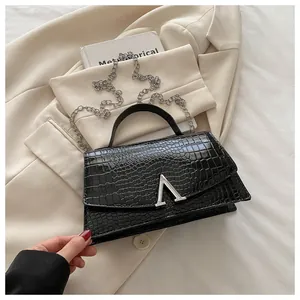 Close-up of black crocodile embossed handbag with silver V-shaped buckle and metal chain