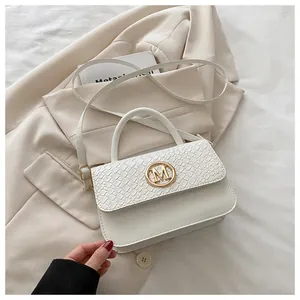 Détail d'un sac à main blanc en cuir avec boucle dorée en M et texture gaufrée crocodile chic
