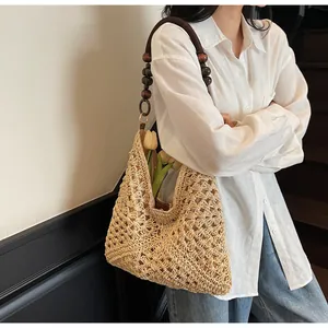 Detail of woven straw tote bag with dark brown wooden bead strap and interior flowers