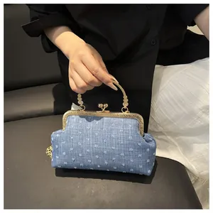 Dettaglio della borsa da sera in denim blu con pois a rilievo e manico dorato ornato