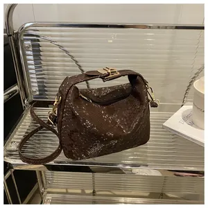 Macro shot of brown snake pattern texture and gold buckle on a stylish crossbody bag