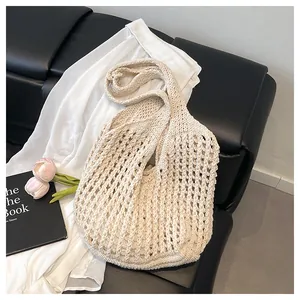 Close-up of cream knit hollow tote bag with intricate mesh weave and wide shoulder strap