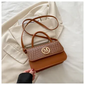 Détail du logo M doré et du motif crocodile brun sur le sac à bandoulière en cuir