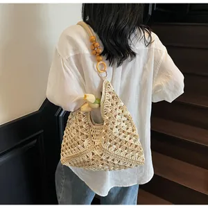 Detail of hand-woven beige straw tote bag featuring decorative wooden beads and acrylic rings