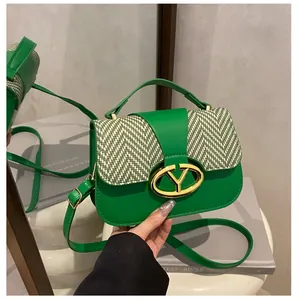 Close-up of green leather handbag with patterned flap and golden oval buckle detail