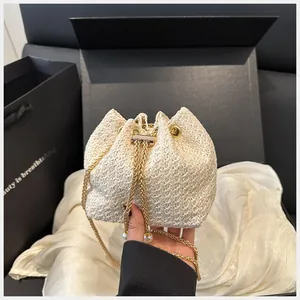 Détail du sac seau en paille tissée avec cordon et bandoulière chaîne perlée dorée