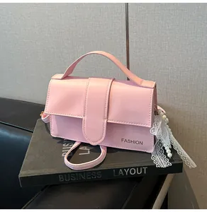 Detailed shot of pink PU leather handbag featuring lace and pearl charms on black book