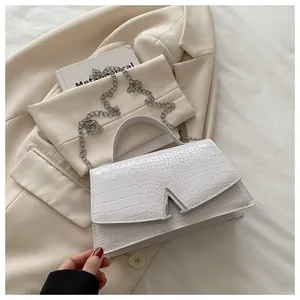 Detail of white crocodile embossed handbag with silver V-shaped buckle and metal chain