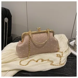 Dettaglio della borsa da sera in tessuto rosa con cornice dorata e manico ad anello