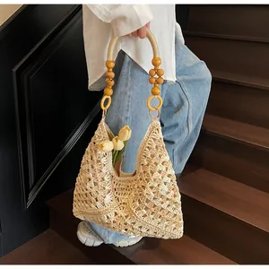 Detail of woven straw tote bag with yellow wooden bead handle and floral pattern