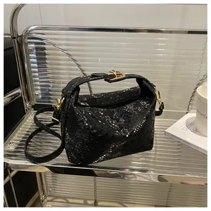 Detail of black snakeskin texture handbag with elegant gold hardware and square lock