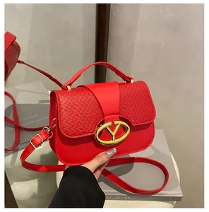 Macro view of red handbag featuring woven texture flap and gold geometric lock buckle