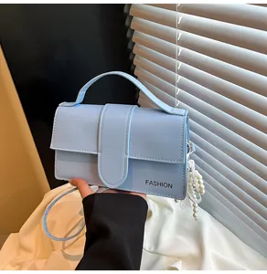 Close-up of light blue handbag featuring pearl tassel and FASHION text detail