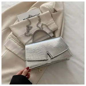 Close-up of silver crocodile embossed handbag with metal V buckle and chain strap