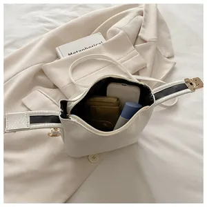 Overhead view showing interior capacity of white crossbody bag with snakeskin strap