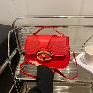 Red flap shoulder bag with weave texture and golden V-logo lock on a display stand