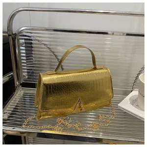 Detailed close-up of golden crocodile pattern texture and metallic A-logo buckle on handbag