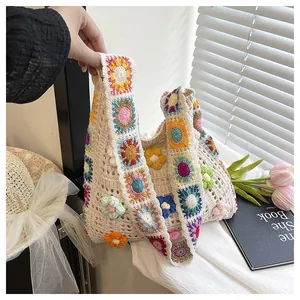 Detail of handmade crochet handbag featuring colorful floral patterns and a wide strap