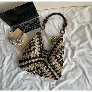 Close-up of handmade woven tote bag with wooden bead handle and black geometric pattern