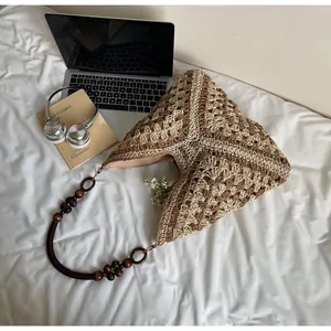 Detail of woven tote bag with contrast geometric pattern and brown wooden bead strap