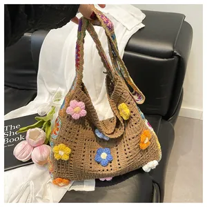 Close-up of handmade knit shoulder bag with 3D colorful crochet flowers and striped strap