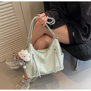 Dettaglio della borsa a tracolla verde chiaro increspata con zip metalliche e ciondolo nuvola