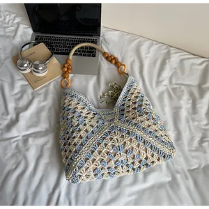 Detail of hand-crocheted blue and beige tote bag with natural wood bead handles and patterns