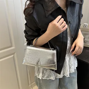 Silver crocodile texture handbag with chain strap and metal A-shaped clasp on a model