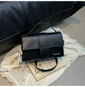 Close-up of black faux leather shoulder bag with gold logo and pearl lace pendant charm