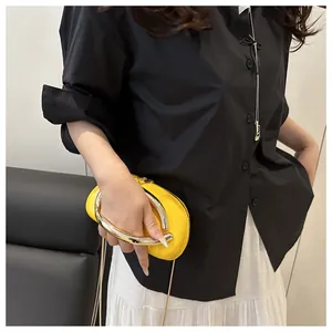Détail d'un sac en cuir verni jaune avec poignée circulaire en argent et bandoulière