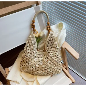 Detail of hand-woven straw tote bag featuring decorative wooden bead handles and floral patterns