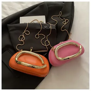 Détail de sacs à main en cuir verni brillant orange et rose avec poignées en métal doré en U