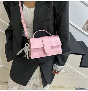 Pink PU leather flap bag with pearl lace bow charm shown on a white lace dress