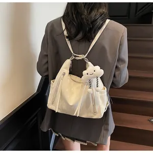 Elegante zaino beige con cerniere decorative e ciondolo a nuvola indossato da modella